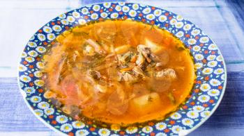 plate with shchi (traditional russian cabbage soup) on on a table covered with a blue tablecloth