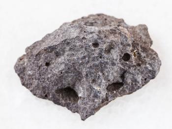 macro shooting of natural mineral rock specimen - pebble of gray basalt stone on white marble background