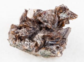 macro shooting of natural mineral rock specimen - rough crystals of axinite stone on white marble background