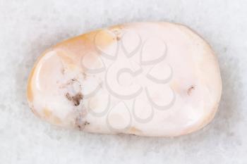 macro shooting of natural mineral rock specimen - polished pink opal gemstone on white marble background from Peru
