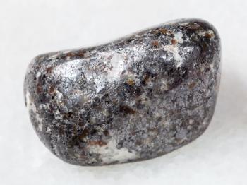 macro shooting of natural mineral rock specimen - pebble of magnetite stone on white marble background from Kovdor district of Kola Peninsula, Russia
