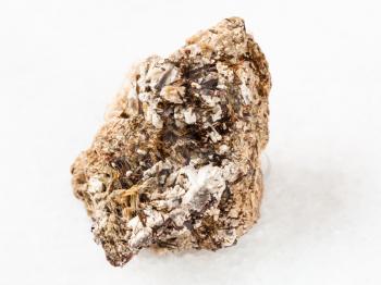macro shooting of natural mineral rock specimen - brown Astrophyllite crystals in raw Natrolite stone on white marble background from Khibiny Mountains, Kola Peninsula, Russia