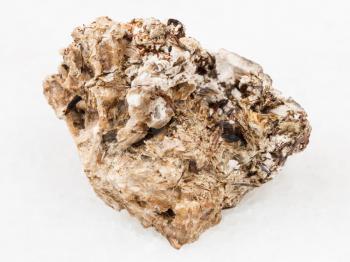 macro shooting of natural mineral rock specimen - brown Astrophyllite crystals in Natrolite stone on white marble background from Khibiny Mountains, Kola Peninsula, Russia
