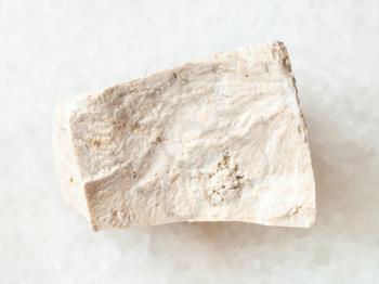 macro shooting of natural mineral rock specimen - rough chemical limestone stone on white marble background