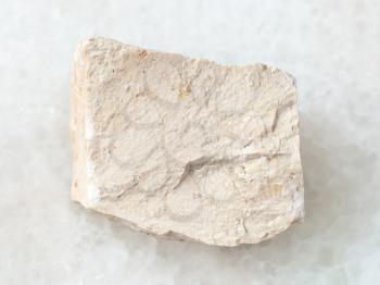 macro shooting of natural mineral rock specimen - raw chemical limestone stone on white marble background