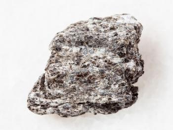macro shooting of natural mineral rock specimen - piece of quartz-biotite schist stone on white marble background