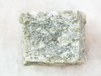 macro shooting of natural mineral rock specimen - quartz-mica schist stone on white marble background