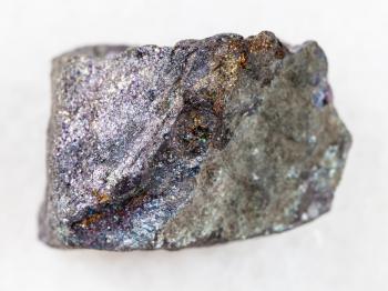 macro shooting of natural mineral rock specimen - rough bornite stone on white marble background from Dashkasan District in Azerbaijan