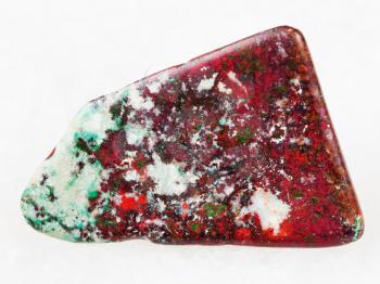 macro shooting of natural mineral rock specimen - tumbled red Cuprite and green Chrysocolla gemstone on white marble background from Milpillas mine, Mexico