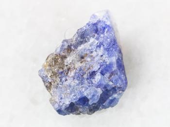 macro shooting of natural mineral rock specimen - raw crystal of Tanzanite gemstone on white marble background from Tanzania