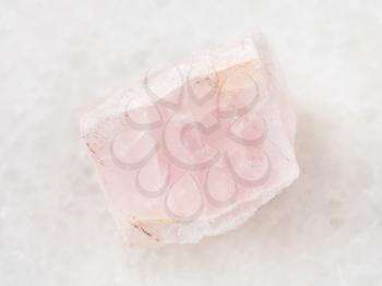 macro shooting of natural mineral rock specimen - crystal of morganite (pink beryl) gemstone on white marble background from Mozambique