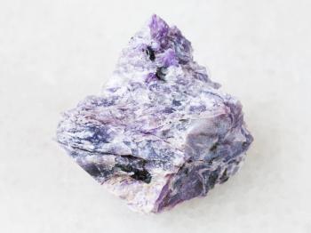 macro shooting of natural mineral rock specimen - piece of charoite stone on white marble background from Murun Massif, Yakutia, Russia