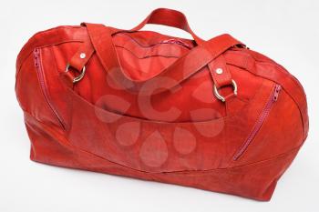 above view of closed red travel bag on white background