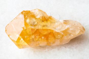 macro shooting of natural rock specimen - raw crystal of Citrine (yellow quartz) gemstone on white marble background from Brazil