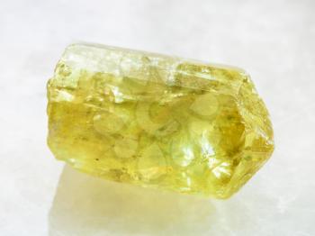macro shooting of natural rock specimen - raw crystal of yellow Apatite gemstone on white marble background from Mexico