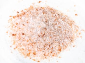 handful of ground pink himalayan salt on white plate close up