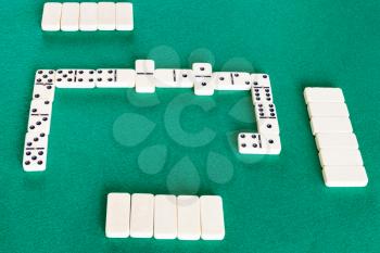 playfield of dominoes board game with white tiles on green baize table