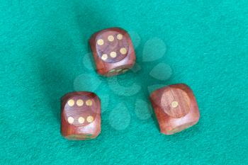 top view of three wooden dices on green baize table close up