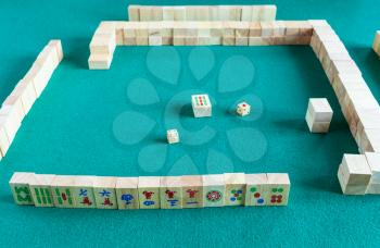 player's set at the beginning of mahjong game , tile-based chinese strategy board game on green baize table