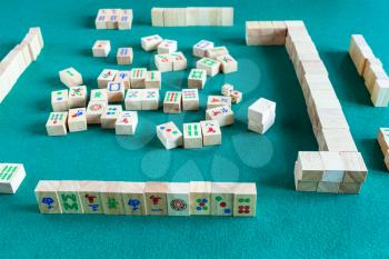playing in mahjong game, tile-based chinese strategy board game on green baize table