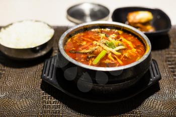korean cuisine - yukgaejang (hot and spicy soup with beef, eggs, mushrooms, starch noodles, scallions, ferns, bean sprouts, served with boiled rice) in metal bowl in local restaurant