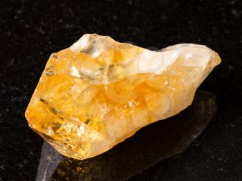 macro shooting of natural rock specimen - raw crystal of Citrine (yellow quartz) gemstone on black granite background from Brazil