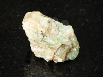 macro shooting of natural mineral - rough chrysoberyl (green beryl) crystal on black granite from Ural Mountains