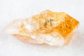 macro shooting of natural rock specimen - rough crystal of Citrine (yellow quartz) gemstone on white marble background from Brazil