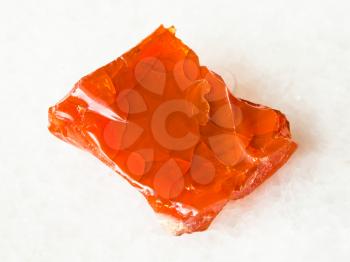 macro shooting of natural mineral - raw fire opal gem stone on white marble from Ural Mountains