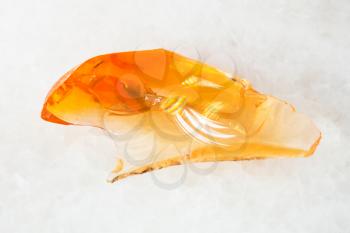 macro shooting of natural mineral - crystal of fire opal gem on white marble from Ural Mountains
