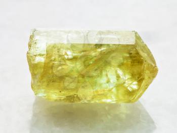 macro shooting of natural rock specimen - crystal of yellow Apatite gemstone on white marble background from Mexico