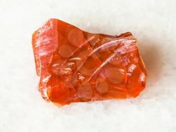 macro shooting of natural mineral - rough fire opal gem stone on white marble from Ural Mountains