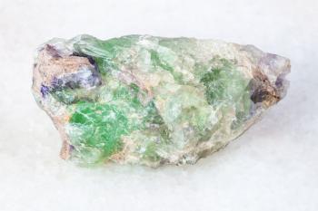 macro shooting of natural mineral - rough green Beryl, Chrysoberyl, Alexandrite gemstone on white marble from Ural Mountains