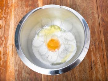 cooking of pie - pile of flour with broken egg in steel bowl