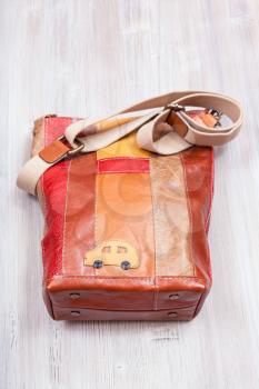 striped brown leather crossbody bag on gray wooden table