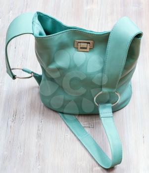 above view of handmade turquoise colour leather handbag on gray wooden table