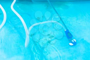 manually vacuuming of outdoor swimming pool in summer day