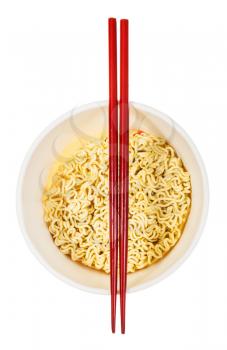red wooden chopsticks on open cup with dried instant noodles isolated on white background