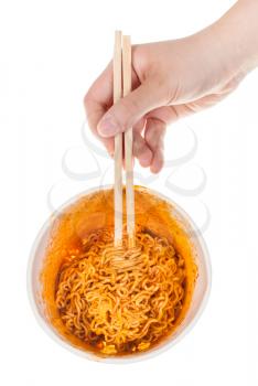 hand keeps wooden chopsticks in prepared spicy instant noodles isolated on white background
