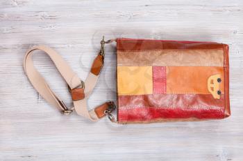 striped brown leather shoulder bag on gray wooden table