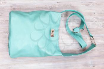 handmade turquoise colour leather shoulder bag on gray wooden table
