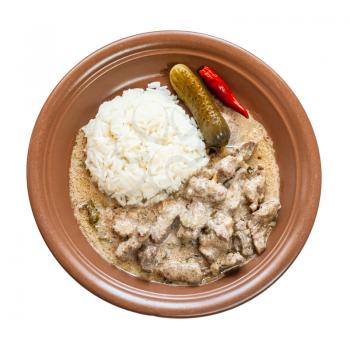 Russian cuisine dish - portion of Beef Stroganoff (Beef Stroganov, Befstroganov) pieces of stewed meat in sour cream on with boiled rice brown plate isolated on white background