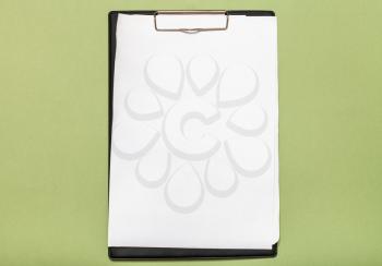 top view of clipboard with blank white paper sheets on dark olive green background