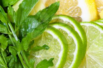 food background - cocktail ingredients, green mint leaves and thin sliced fresh limes, lemons, ginger close up