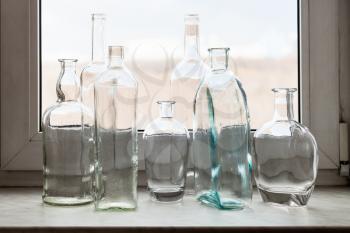 many empty drunk bottles on windowsill of home window on sunny spring day