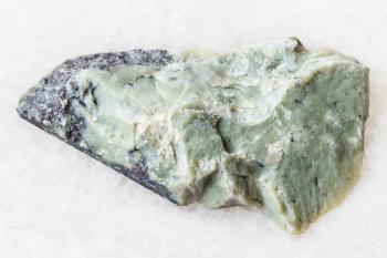 natural mineral from geological collection - rough Teisky Jade (Hantigyrite, khakassian serpentine) rock with Magnetite, Serpentine, Hematite minerals from Teyskoye mine, Khakassia on white marble