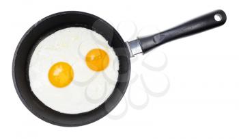 top view of two fried eggs in black frying pan isolated on white background