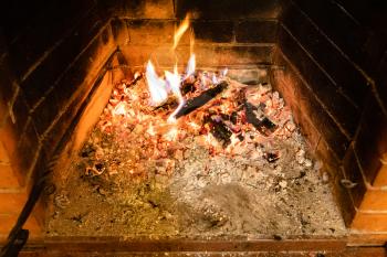 above view of smoldering firewood and ash in home brick fireplace