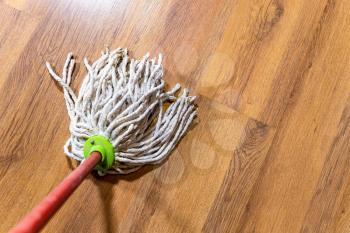 point of view of rope mop is wiping wooden laminate floor at home