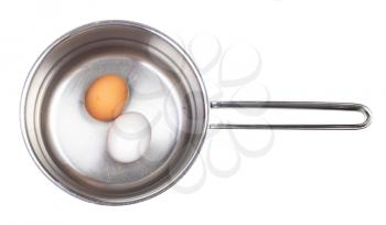 top view of two eggs in saucepan with water isolated on white background